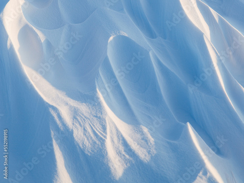 Snow texture. Wind sculpted patterns on snow surface. Wind in the tundra and in the mountains on the surface of the snow sculpts patterns and ridges (sastrugi). Arctic, Polar region. Winter background photo