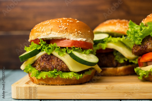 Delicious burgers with lettuce and cheese served on cutting board