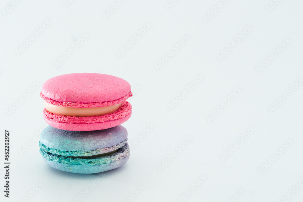 Brightly colored stacked up French macarons on white. Tasty colourful macaroons. Blue and pink macaroons isolated on white background. French pastry made from egg whites. Concept of food, desserts Brightly colored stacked up French macarons on white. Tasty colourful macaroons. Blue and pink macaroons isolated on white background. French pastry made from egg whites. Concept of food, desserts