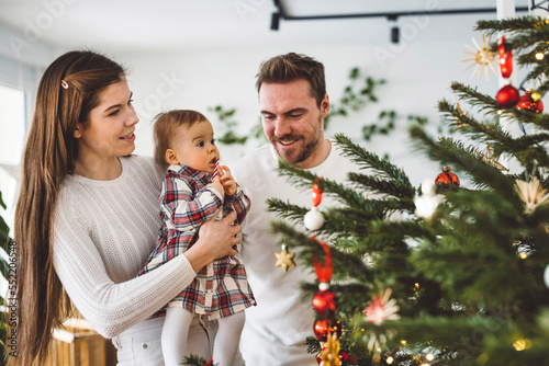 Family of three decorating the Christmas tree together
