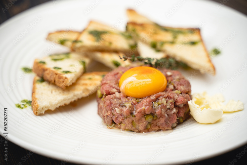 a tasty dish of meat and egg yolk with croutons on a plate. a tasty dish of meat and egg yolk with croutons on a plate.