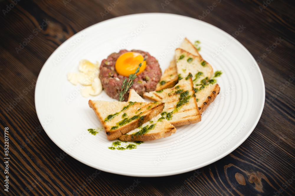 a tasty dish of meat and egg yolk with croutons on a plate.