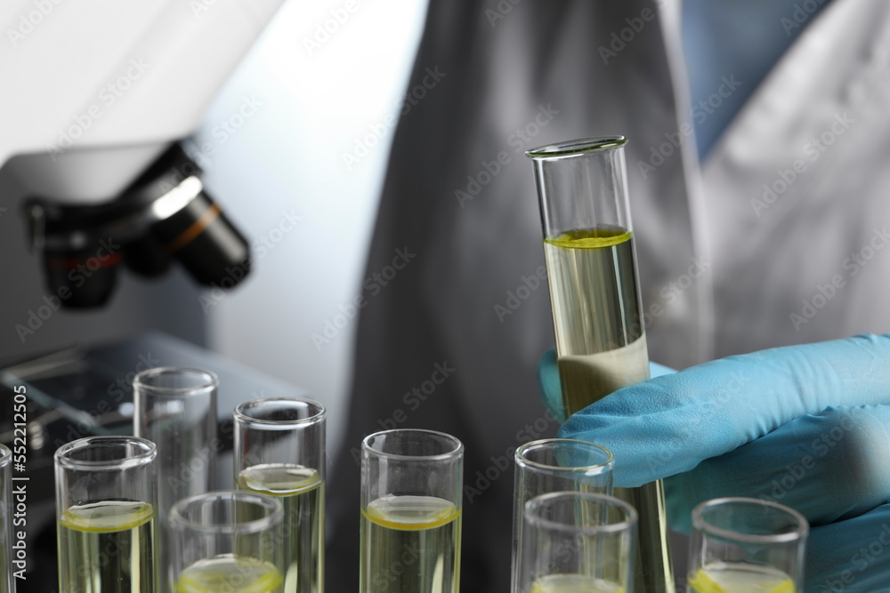 Doctor taking test tube with urine sample for analysis in laboratory, closeup Doctor taking test tube with urine sample for analysis in laboratory, closeup