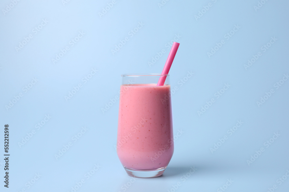 Glass with delicious fresh berry smoothie on light blue background Glass with delicious fresh berry smoothie on light blue background
