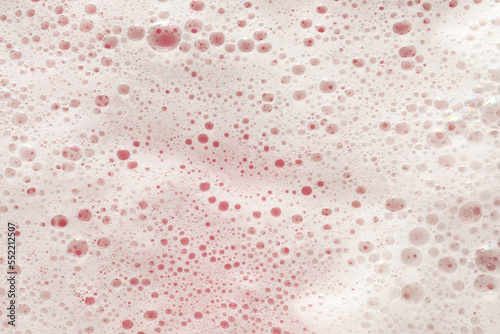 White washing foam on pale pink background, top view