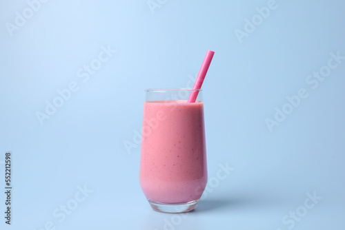 Glass with delicious fresh berry smoothie on light blue background