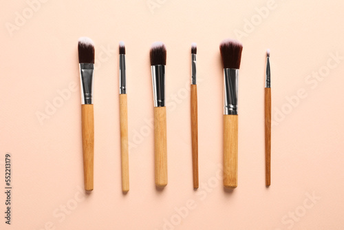 Set of makeup brushes on beige background, flat lay