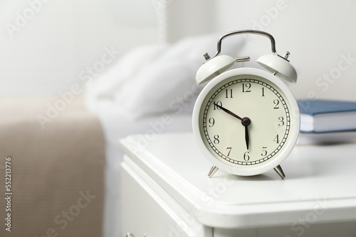 Alarm clock on white nightstand in bedroom, space for text