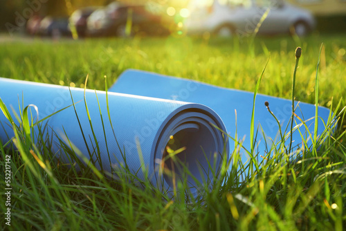 Blue karemat or fitness mat in fresh green grass outdoors, closeup