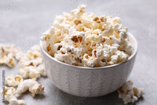 Bowl of tasty popcorn on grey table, closeup