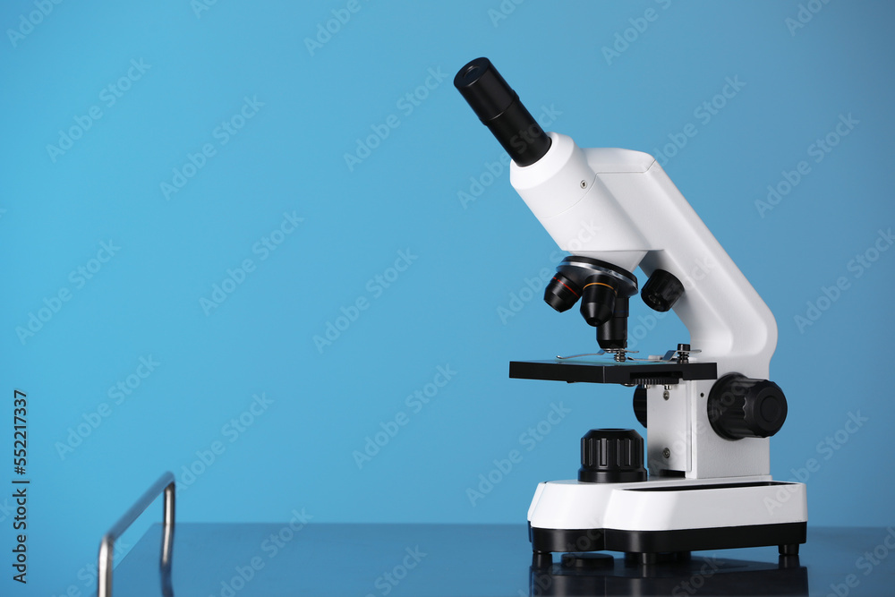 Modern microscope on metal table against blue background. Space for text Modern microscope on metal table against blue background. Space for text