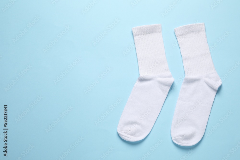 Pair of white socks on light blue background, flat lay. Space for text Pair of white socks on light blue background, flat lay. Space for text