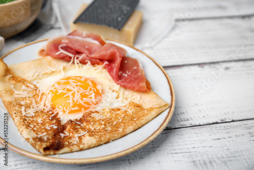 Tableau sur toile Delicious crepe with egg on white wooden table, closeup