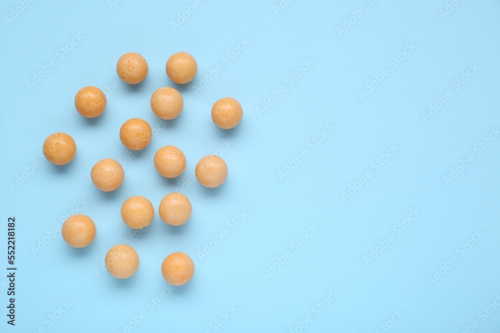Many bright orange gumballs on light blue background, flat lay. Space for text Many bright orange gumballs on light blue background, flat lay. Space for text