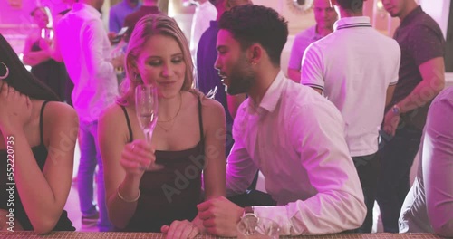 Party, flirt and man and woman talking at New Year celebration event, nightclub or bar with neon light, crowd and music. Champagne, alcohol drinks and communication of people flirting at elegant club