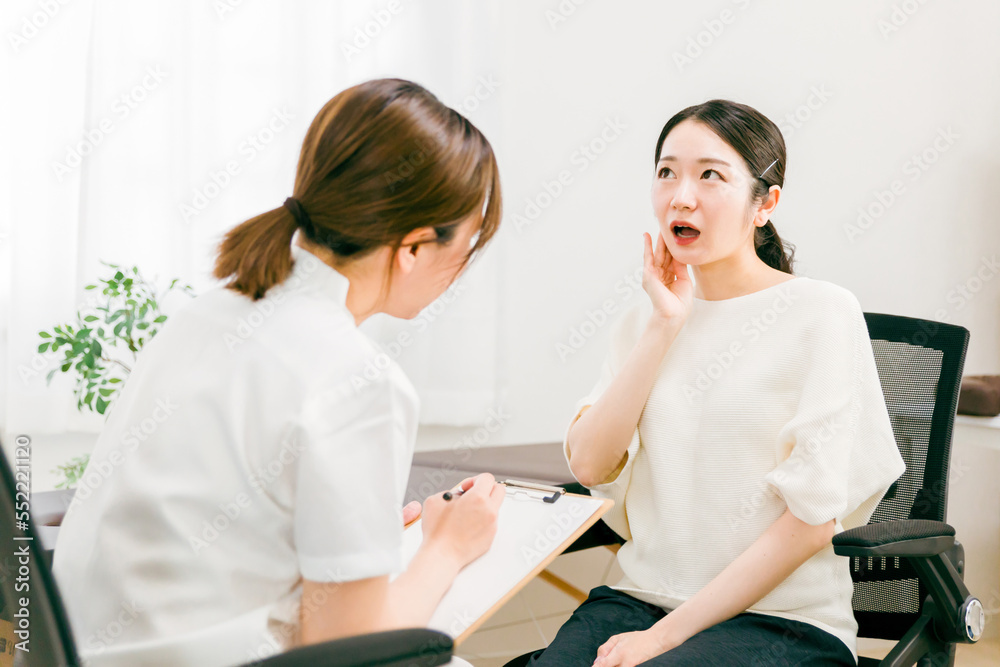 Fototapeta premium 病院・整骨院・整体院であごの痛みで悩む患者を診察・問診・カウンセリングする女性医師・看護師 
