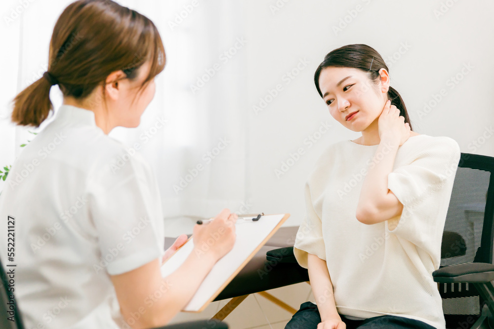 Obraz premium 病院・整骨院・整体院で首の痛みで悩む患者を診察・問診・カウンセリングする女性医師・看護師 