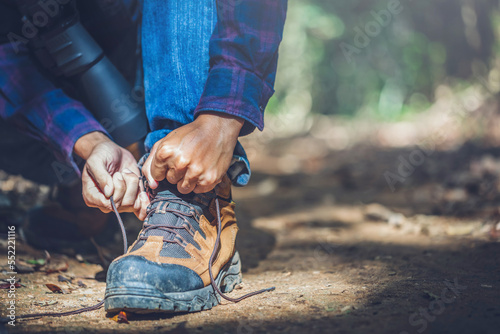 Close up hiker boots and hands tying bootlaces in forest