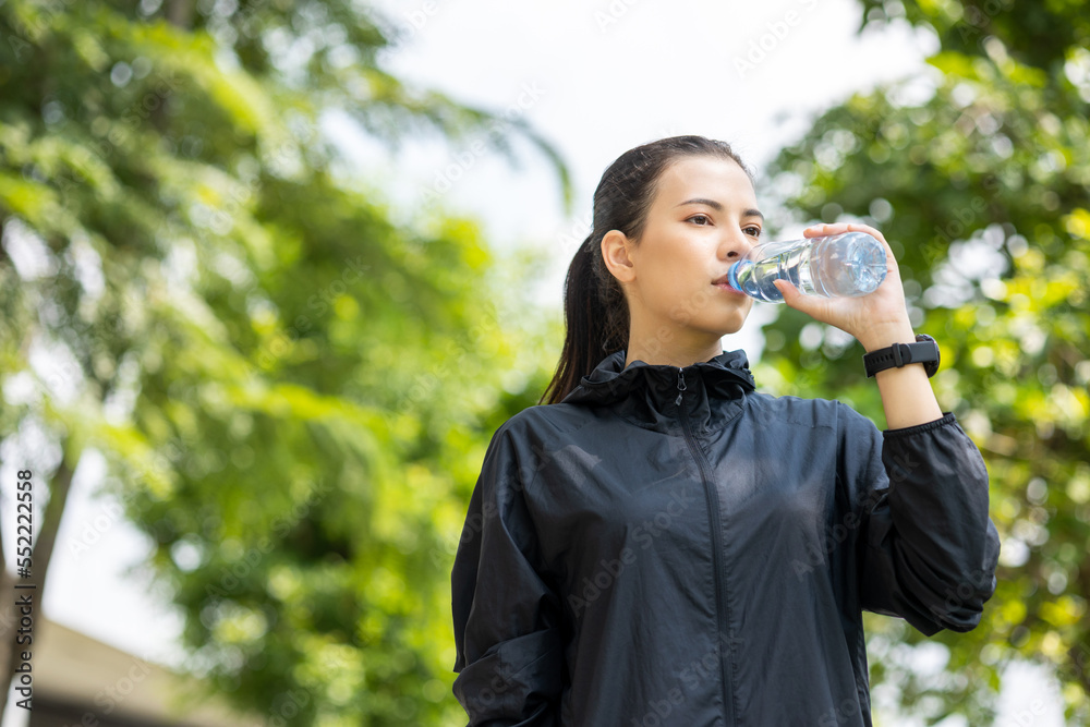 Happy slim woman drinking water after workout exercising in the city at sunrise. Young beautiful asian drinking water after jogging running outdoor. Healthy and active lifestyle concept. Happy slim woman drinking water after workout exercising in the city at sunrise. Young beautiful asian drinking water after jogging running outdoor. Healthy and active lifestyle concept.