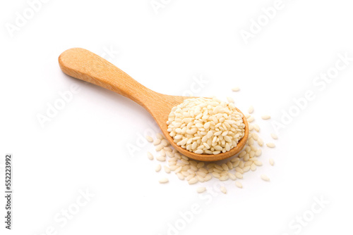 White sesame seeds in wooden spoon isolated on white background.