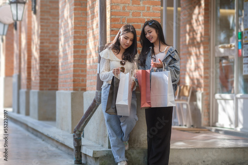 Two beautiful woman friends  looking into shopping bags and talking to each other after shopping.