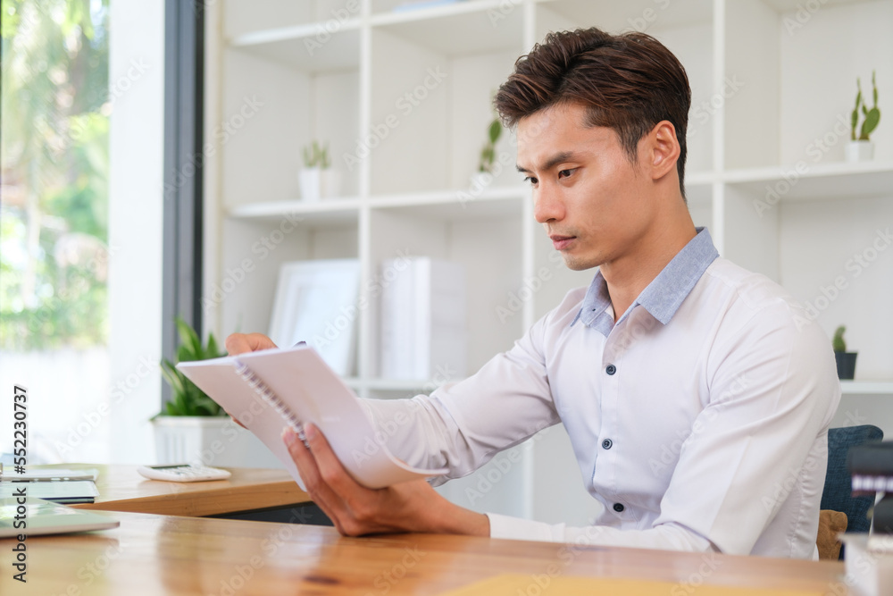 Concentrated asian businessman taking note, planning daily appointment on notebook. Concentrated asian businessman taking note, planning daily appointment on notebook.
