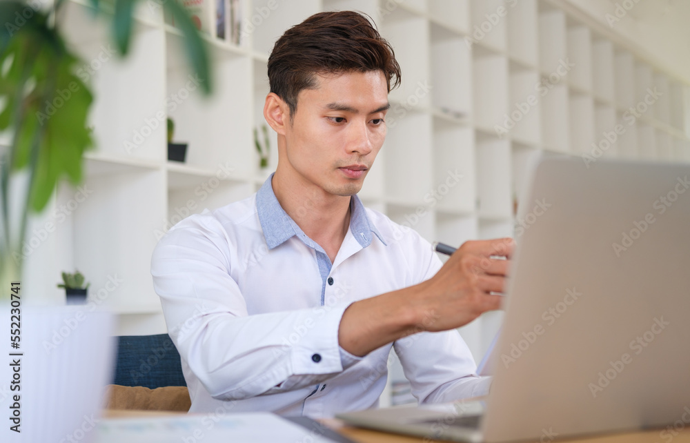 Focused businessman using laptop computer and doing some paperwork at modern workplace. Focused businessman using laptop computer and doing some paperwork at modern workplace.