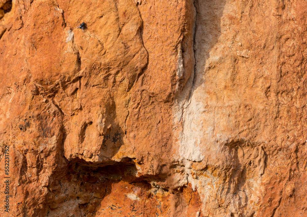Fototapeta premium Sedimentary rocks with a high content of iron oxide. Red soil, loam. The texture of the soil.