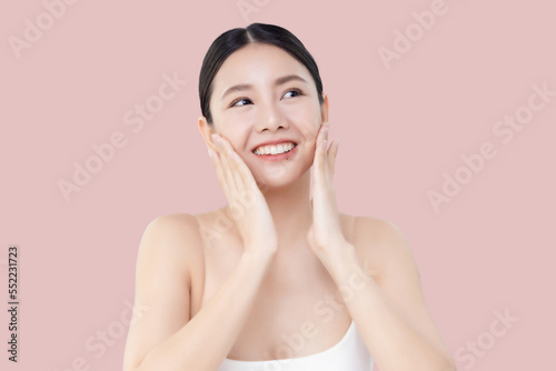 Studio shot Beautiful young Asian woman with clean fresh skin massage her face isolated on pink background.