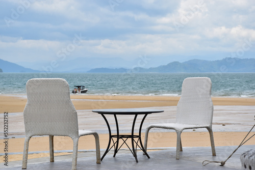 White woven chairs for eating snacks and taking in the sea breeze. © denchai