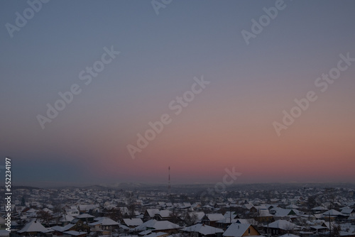 Abstract natural sky background over a provincial town. Space for copy. Morning winter blue-pink sky over the village. Twilight sky background. Winter mountain landscape