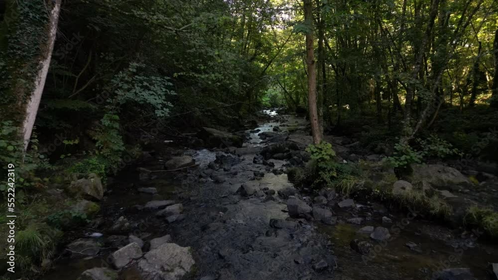 Drone flying over stream crossing forest near Mortain waterfall, Manche in France. Aerial forward low altitude Drone flying over stream crossing forest near Mortain waterfall, Manche in France. Aerial forward low altitude
