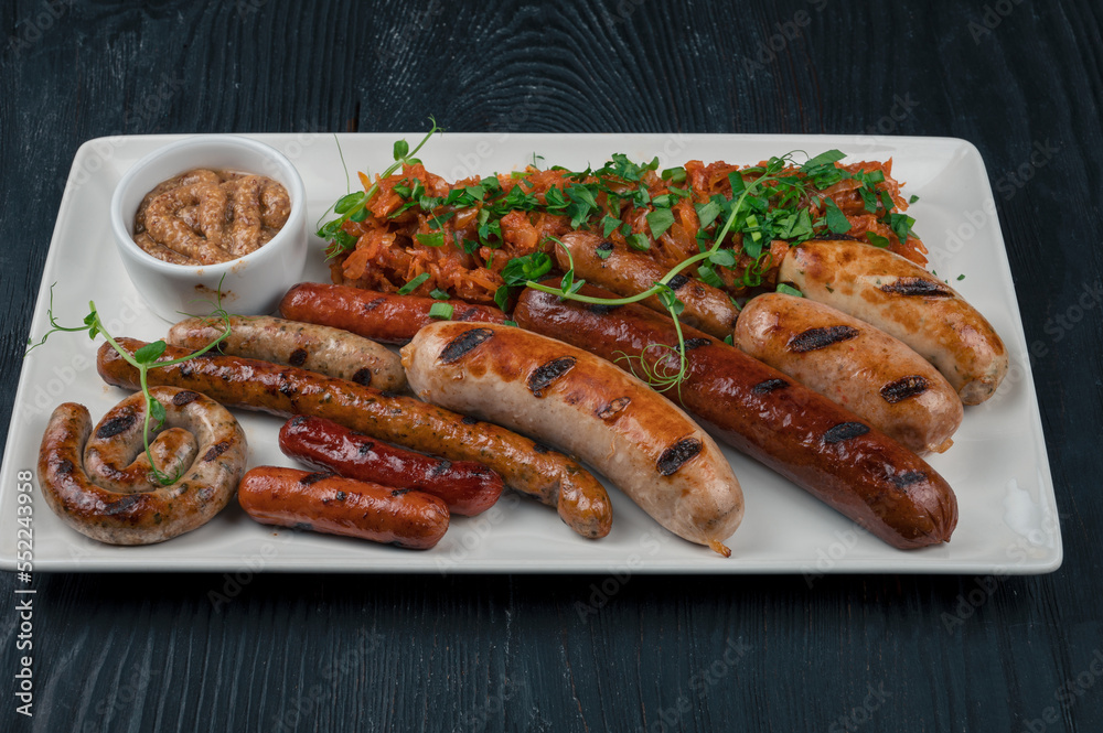 Grilled different sausage with the addition of herbs and horseradish sauce on the plate. Grilling food, bbq, barbecue concept Grilled different sausage with the addition of herbs and horseradish sauce on the plate. Grilling food, bbq, barbecue concept
