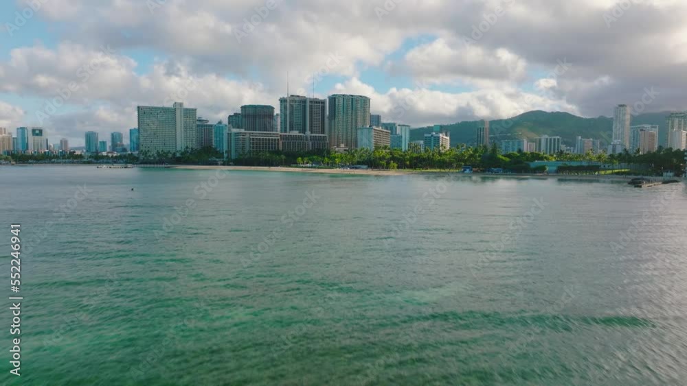 Flying above cyan green ocean toward Hawaii coastal hotel skyline; drone Flying above cyan green ocean toward Hawaii coastal hotel skyline; drone