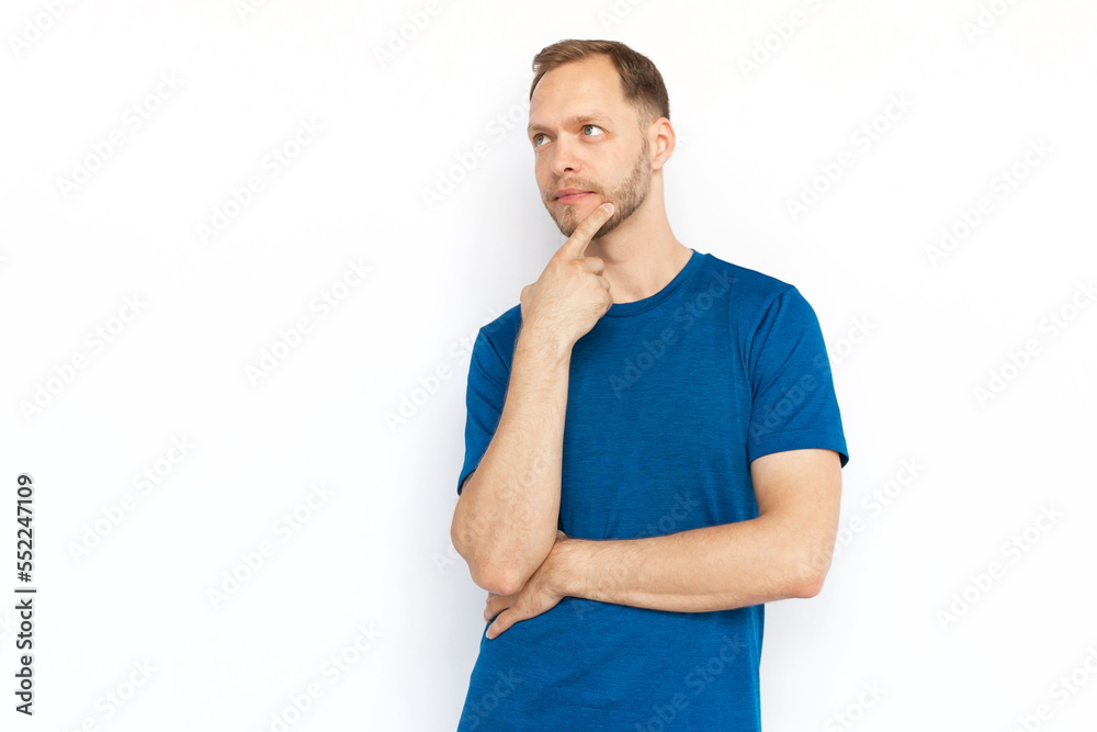 Pensive Caucasian man thinking and looking up. Concentrated guy touching chin with finger, considering ideas or dreaming while standing on white background. Imagination, wonder, inspiration concept Pensive Caucasian man thinking and looking up. Concentrated guy touching chin with finger, considering ideas or dreaming while standing on white background. Imagination, wonder, inspiration concept