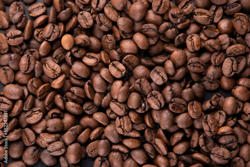 portion background of organic coffee beans direct from the Brazilian producer roasted arabica type spilled and scattered on a black background portrait texture