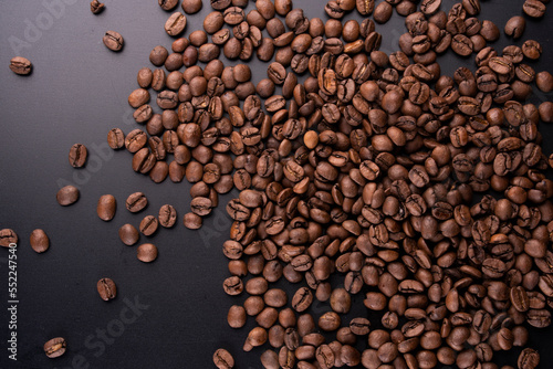 portion background of organic coffee beans direct from the Brazilian producer roasted arabica type spilled and scattered on black background gray gradient portrait texture