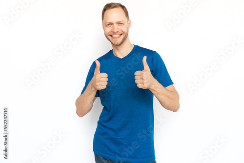 Happy Caucasian man smiling and showing thumbs up gestures. Cheerful bearded man standing on white background, rejoicing and showing approving gestures. Agreement, approval, happiness concept