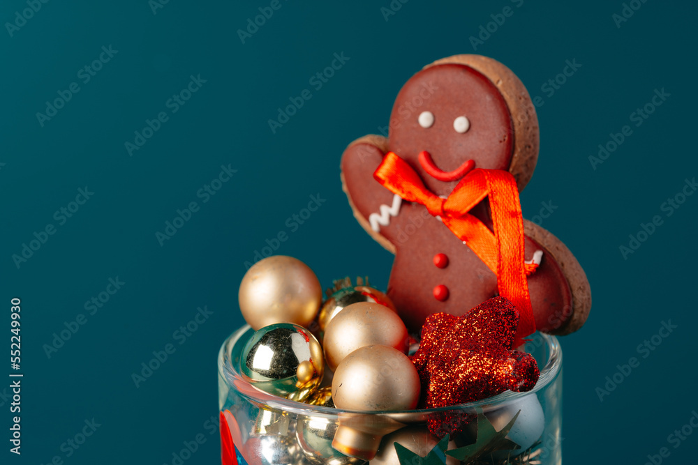Glass with Christmas decorations on dark green background