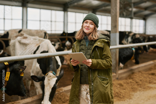 Portrait of young farmer using digital tablet to watch information about each milk cow during her work on farm