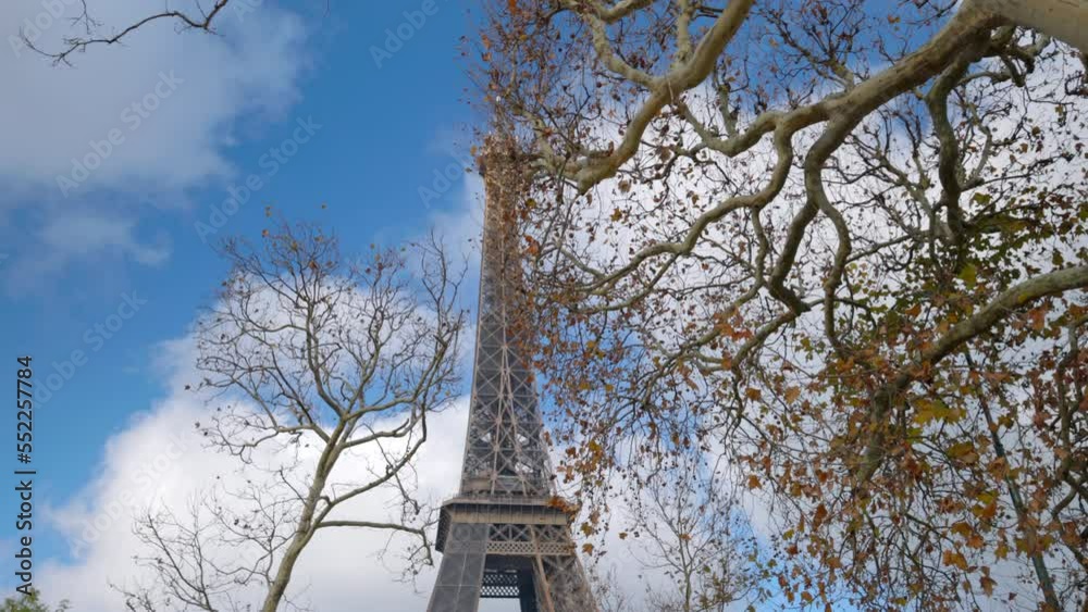 View through threes on Eiffel Tower on Champs de Mars in Paris, France. Beautiful French architecture. Cloudy sky. Tourism, famous destinations. Handheld shot. High quality 4k footage View through threes on Eiffel Tower on Champs de Mars in Paris, France. Beautiful French architecture. Cloudy sky. Tourism, famous destinations. Handheld shot. High quality 4k footage