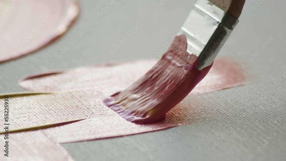 Macro shot close up of brush with yellow-pink paint that glides across canvas. artist paint his picture in oil or acrylic. Emotional drawing of abstract picture.