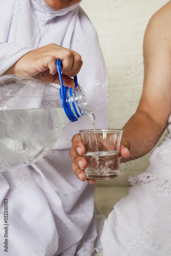 Close up of hijab woman hands pouring zamzam water into the glass photo