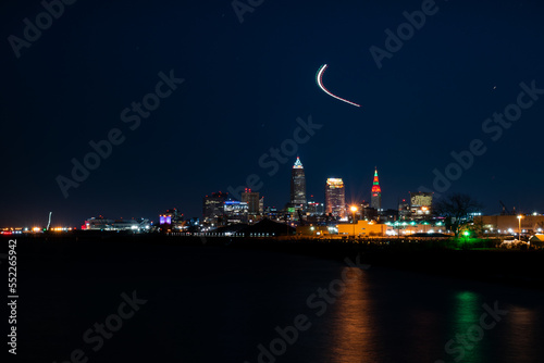 Long exposure cityscape at nighttime with airplane path.