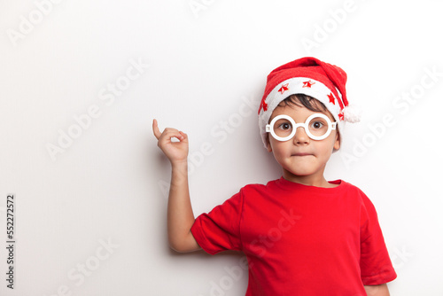 A child in Santa's red hat and white funny glasses on a white background. Studio. 