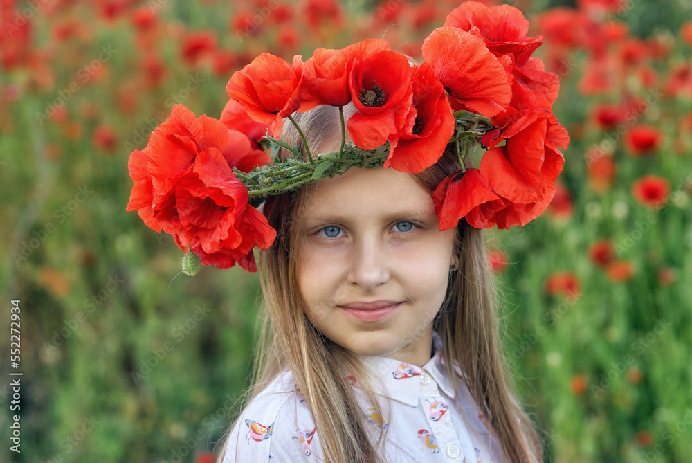 Portrait of a beautiful young girl in a wreath of red poppies in nature