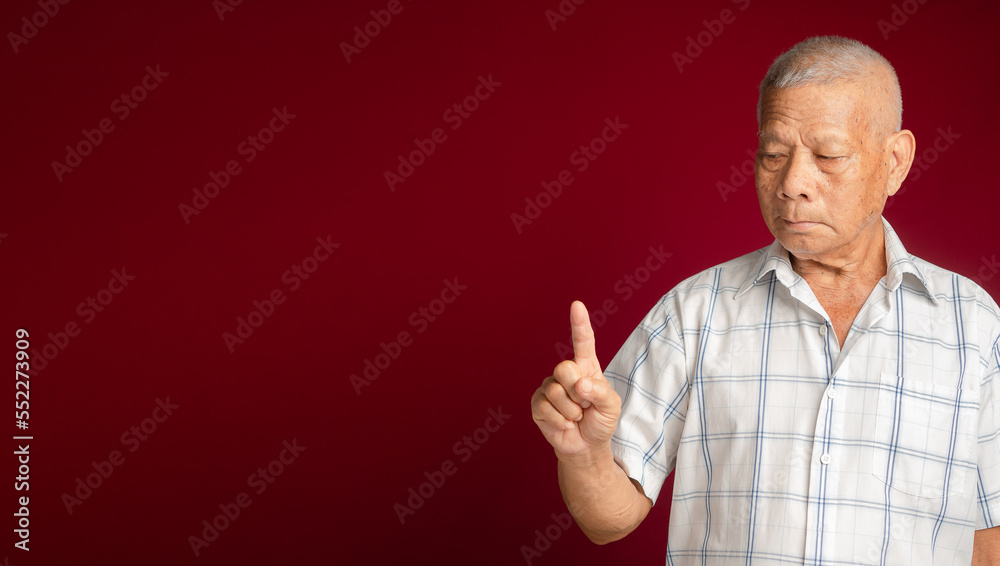Naklejka premium Senior man in a white shirt showing a finger with a smile while standing on a red background
