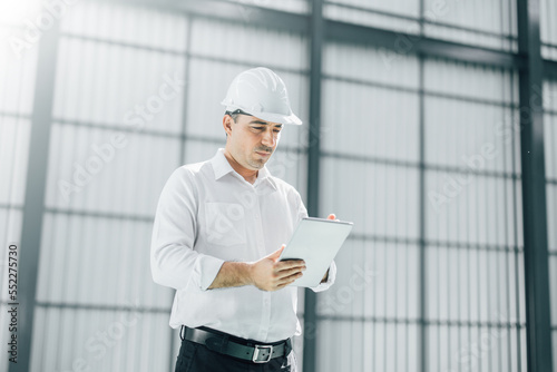 warehouse manager with tablet and ..radio communication his worker working in background in warehouse distribution center environment. Business warehouse inventory,contruction warehouse