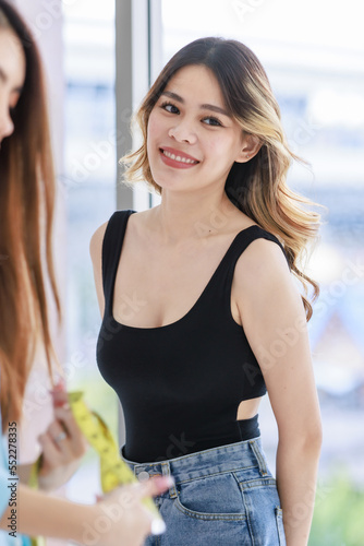 Millennial Asian young beautiful sexy female customer in black tank top and jeans outfit standing waiting for professional dressmaker designer seamstress in tailor studio workshop office Free Download Millennial Asian young beautiful sexy female customer in black tank top and jeans outfit standing waiting for professional dressmaker designer seamstress in tailor studio workshop office - GFXLoad