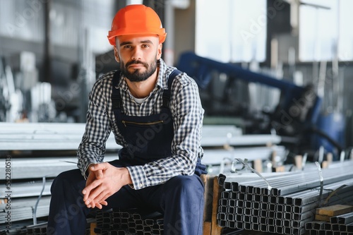 Happy Professional Heavy Industry Engineer Worker Wearing Uniform, and Hard Hat in a Steel Factory. Smiling Industrial Specialist Standing in a Metal Construction Manufacture